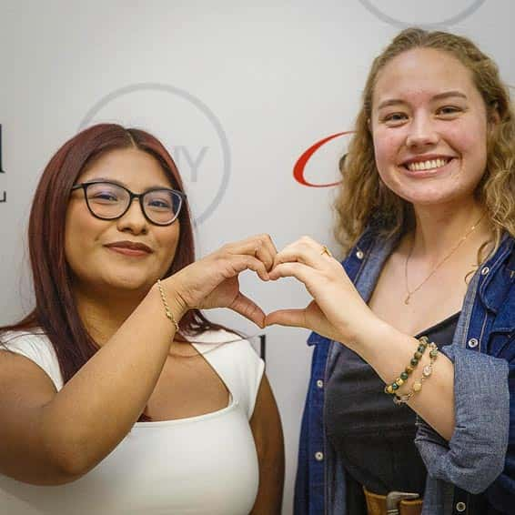 Two scholarship recipients making a heart with their hands