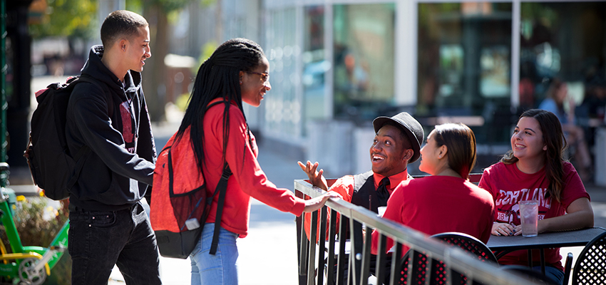 Students chat outside Brix restaurant on Main Street in Cortland