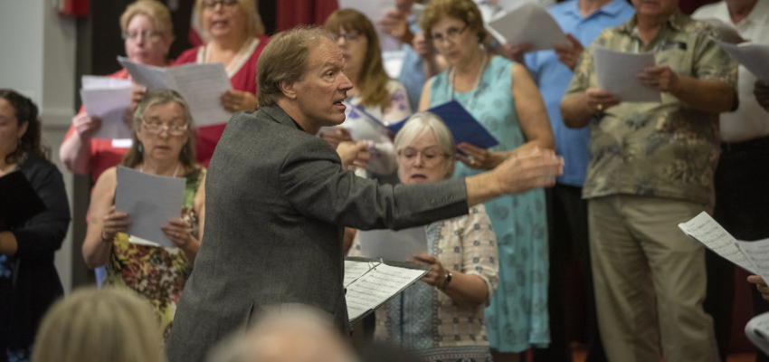 An enthusiastic conductor in from of a chorus.