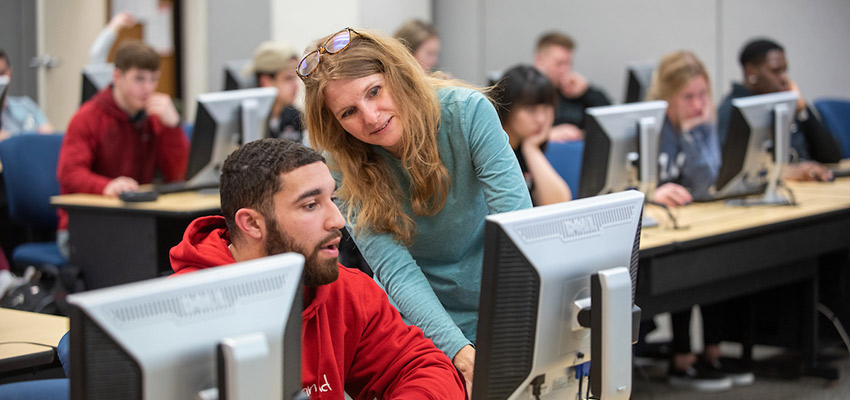 Computer Applications instructor assisting a student in the computer lab