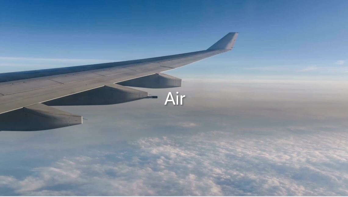 Plane wing flying over clouds through blue sky