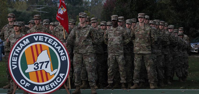 Battalion standing in formation behind a Vietnam Veterans of America sign