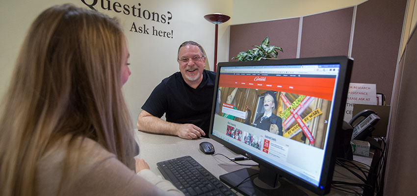 Student receives assistance from a librarian at Research Help desk.