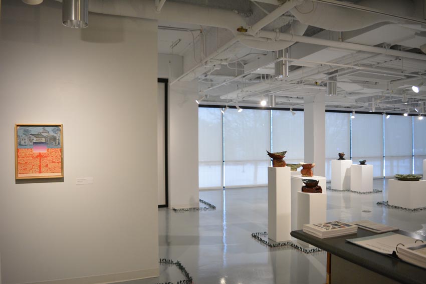 View into the central gallery at Dowd Gallery featuring sculptural objects produced by Jeremiah Donovan, professor of ceramics, Jillian McEvoy, a painting by Stephen Alexander Clark, processor of painting, and floor installation by Bryan Valentine Thomas, instructor of design and drawing, at the Art and Art History Department.